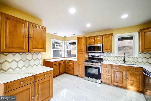 kitchen with appliances with stainless steel finishes, tasteful backsplash, a wealth of natural light, and sink