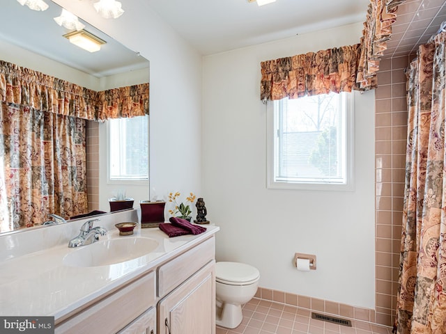 bathroom with tile patterned flooring, plenty of natural light, toilet, and vanity