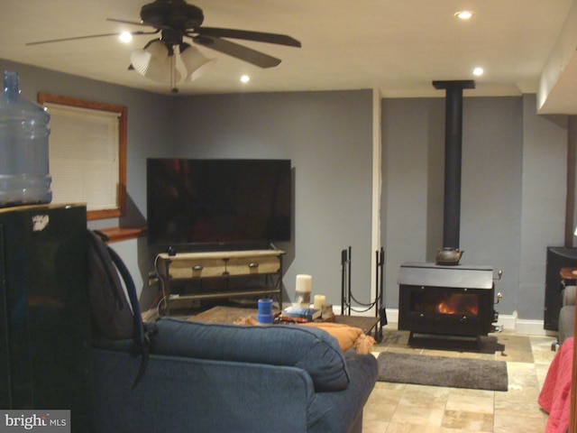 living room featuring ceiling fan and a wood stove