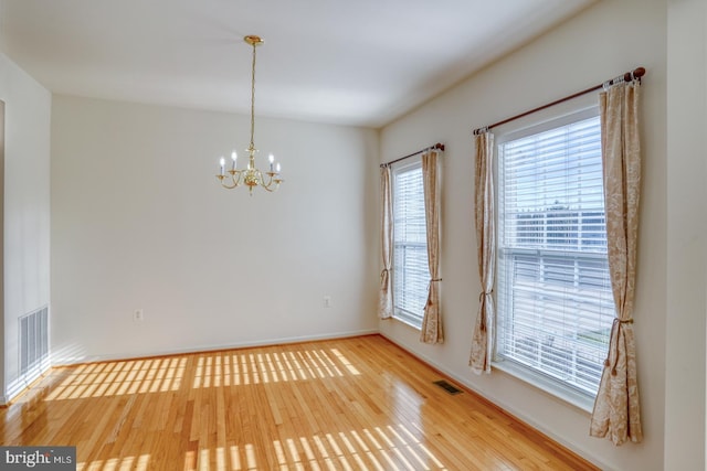 empty room with hardwood / wood-style floors and a chandelier