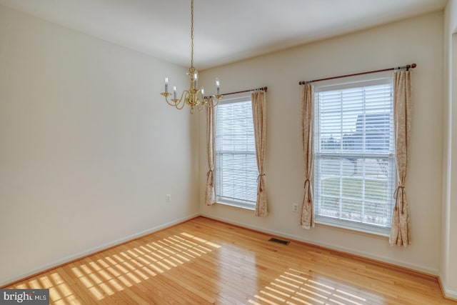 unfurnished room featuring hardwood / wood-style flooring and an inviting chandelier