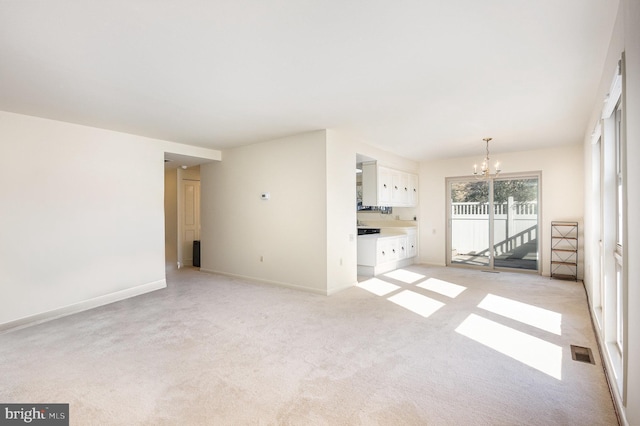 unfurnished living room featuring light carpet and a notable chandelier