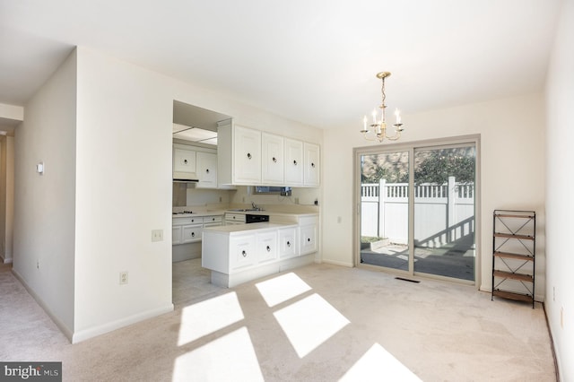 kitchen with a notable chandelier, light colored carpet, and white cabinets