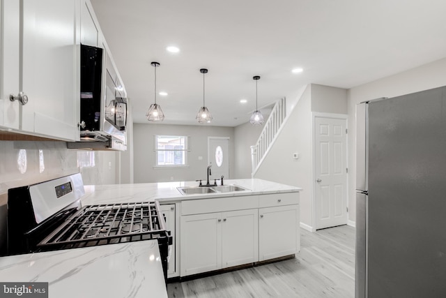 kitchen with white cabinetry, sink, decorative light fixtures, and appliances with stainless steel finishes