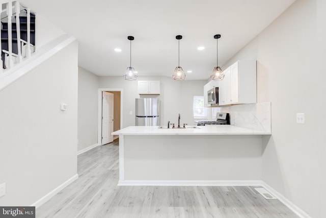 kitchen with kitchen peninsula, appliances with stainless steel finishes, white cabinets, and sink