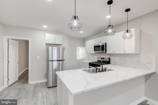 kitchen featuring kitchen peninsula, pendant lighting, stainless steel appliances, and white cabinetry