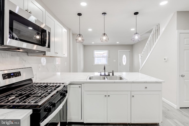 kitchen with white cabinets, pendant lighting, stainless steel appliances, and sink