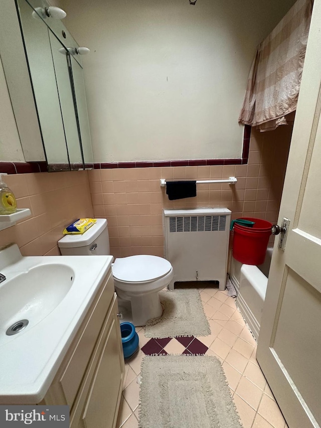 bathroom with radiator heating unit, vanity, tile walls, and toilet