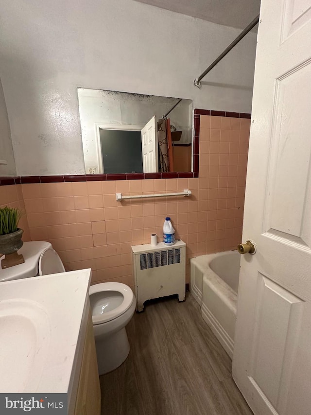 full bathroom featuring vanity, radiator, toilet, tile walls, and wood-type flooring