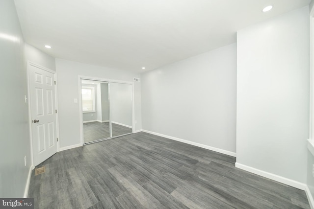 unfurnished bedroom with a closet and dark wood-type flooring