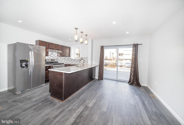 kitchen with pendant lighting, sink, dark hardwood / wood-style floors, appliances with stainless steel finishes, and kitchen peninsula