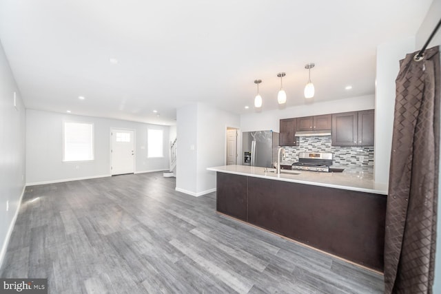 kitchen featuring sink, stainless steel appliances, tasteful backsplash, pendant lighting, and dark brown cabinets