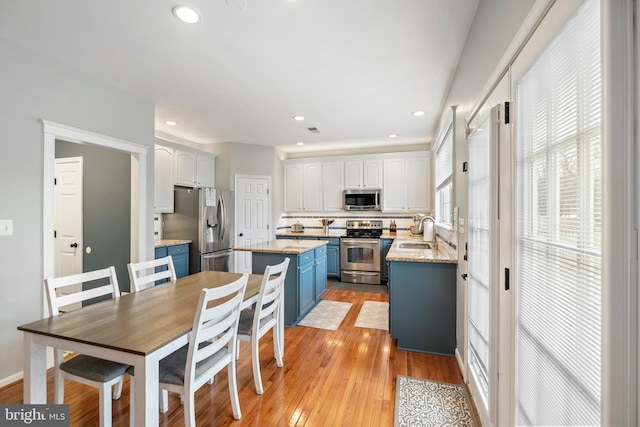 kitchen featuring sink, appliances with stainless steel finishes, white cabinetry, a kitchen island, and blue cabinets