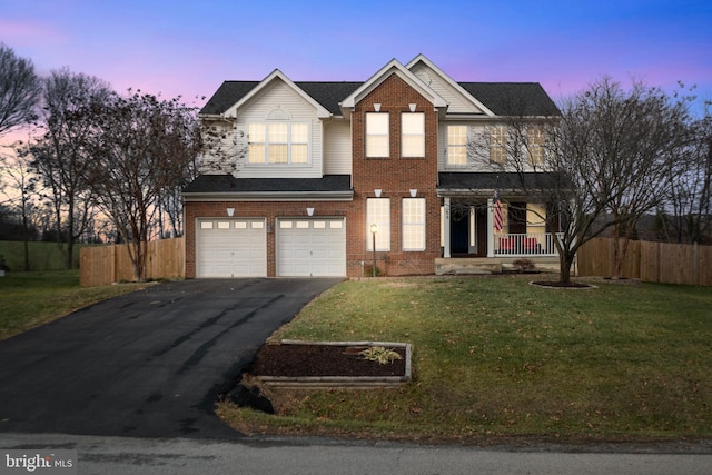 view of front of property featuring a yard, a garage, and a porch