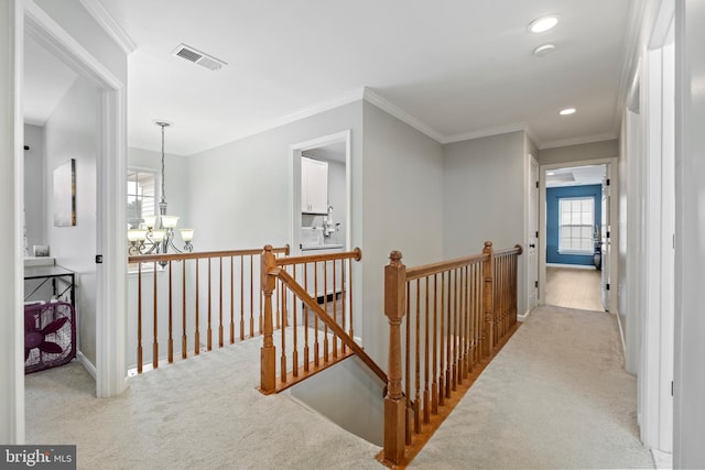 hallway with light carpet, ornamental molding, and an inviting chandelier