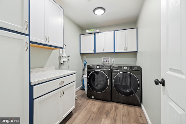 washroom with cabinets, light hardwood / wood-style floors, and washer and dryer