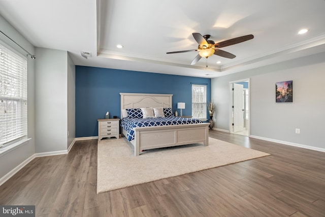 bedroom with a tray ceiling, wood-type flooring, and ceiling fan