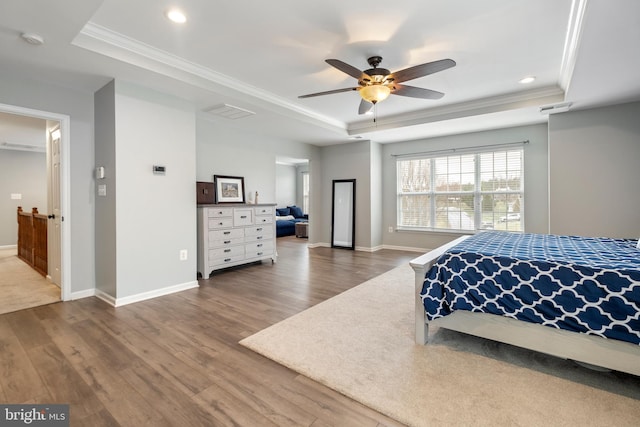 bedroom featuring hardwood / wood-style floors, ornamental molding, a raised ceiling, and ceiling fan