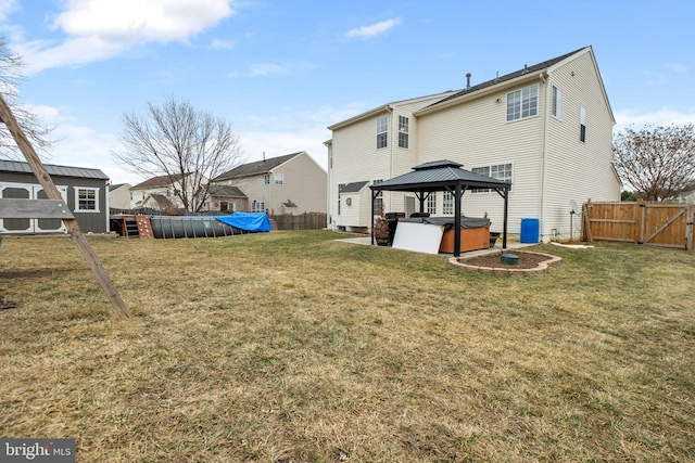 rear view of property with a gazebo, a swimming pool with hot tub, and a yard