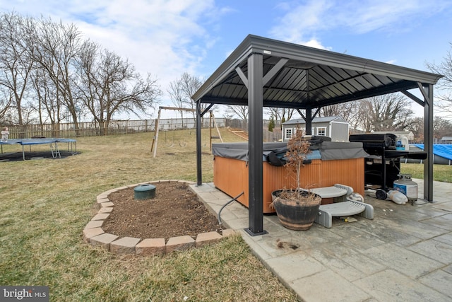 view of patio / terrace with a storage unit, a hot tub, a playground, and a trampoline