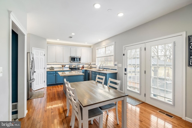 kitchen with blue cabinetry, a center island, stainless steel appliances, decorative backsplash, and white cabinets