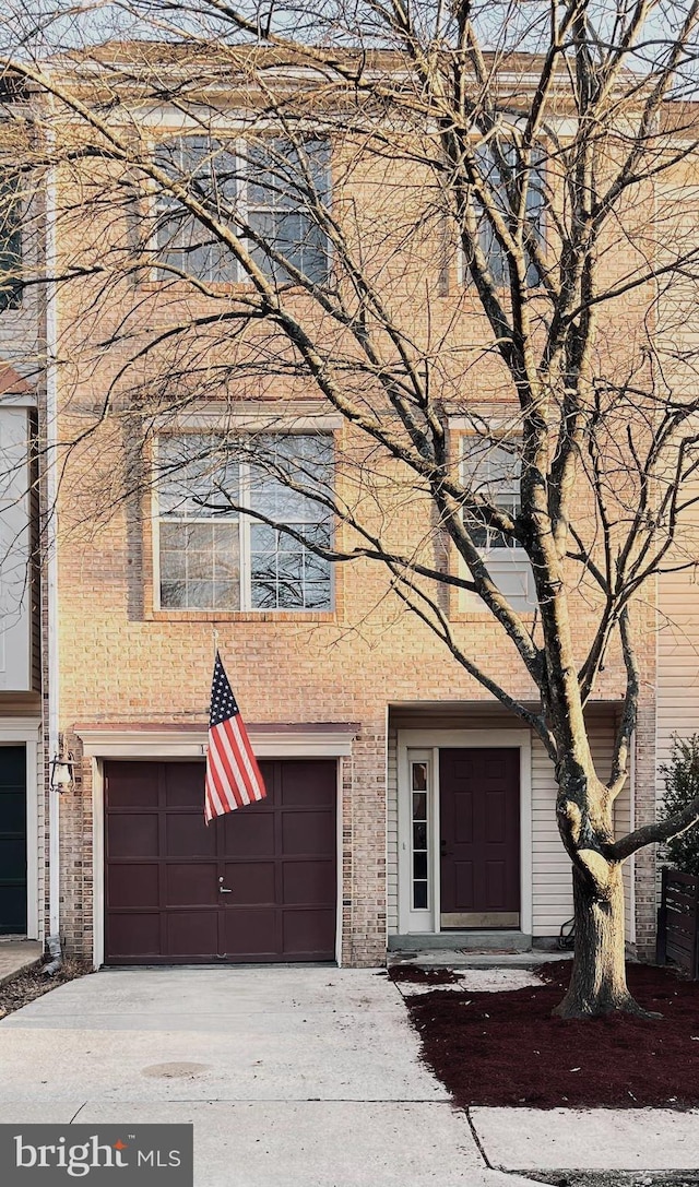 multi unit property featuring brick siding, a garage, and driveway