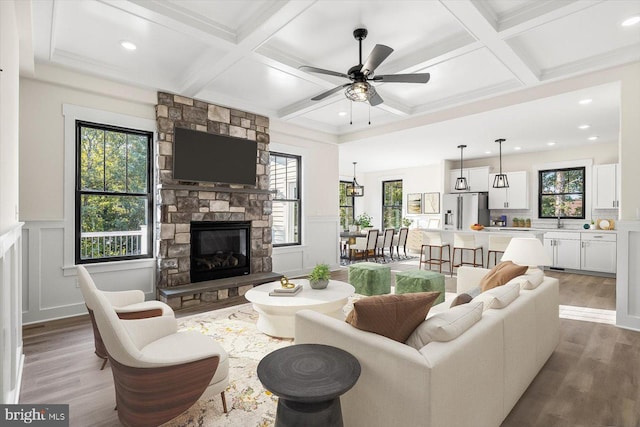 living room with plenty of natural light, a stone fireplace, and coffered ceiling