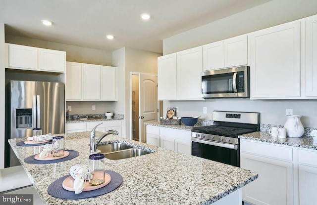 kitchen featuring white cabinets, appliances with stainless steel finishes, a center island with sink, and sink