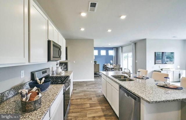 kitchen featuring appliances with stainless steel finishes, a center island with sink, white cabinetry, and sink