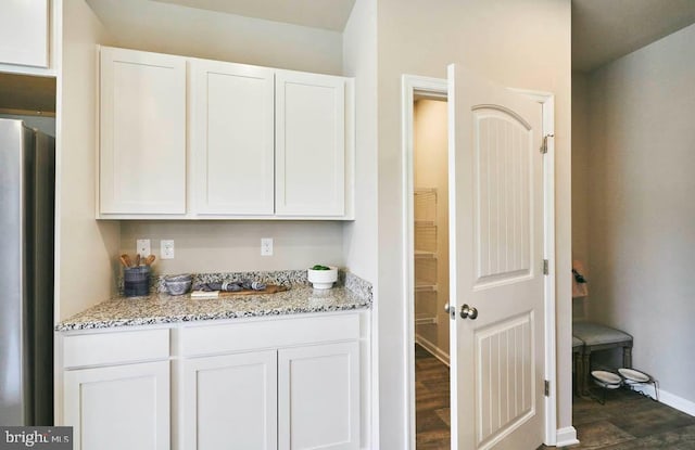 bar with dark hardwood / wood-style flooring, white cabinetry, stainless steel refrigerator, and light stone counters