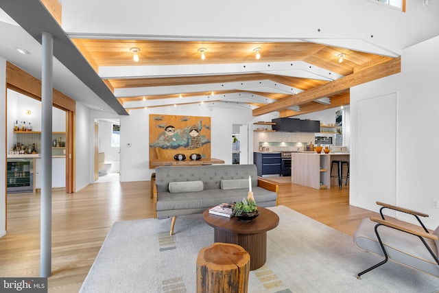 living area with light wood finished floors, a bar, wine cooler, and lofted ceiling with beams