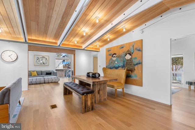 dining room with lofted ceiling with beams, light wood-type flooring, and a healthy amount of sunlight