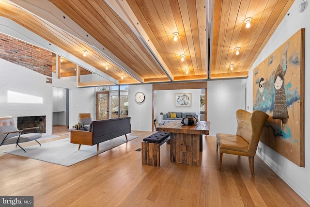 sitting room with a brick fireplace, wooden ceiling, and beamed ceiling