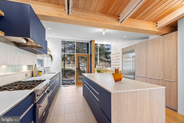 kitchen featuring blue cabinetry, wall chimney exhaust hood, floor to ceiling windows, and high end appliances