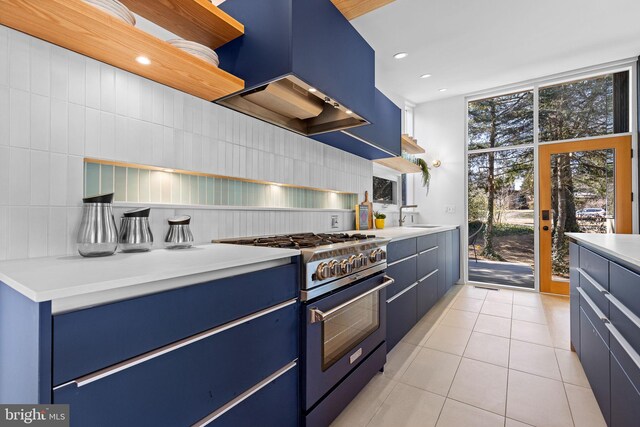 kitchen with light tile patterned floors, blue cabinets, high end stainless steel range oven, expansive windows, and custom range hood