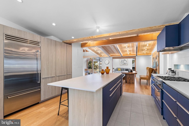 kitchen with a breakfast bar, high end appliances, a kitchen island, modern cabinets, and blue cabinets