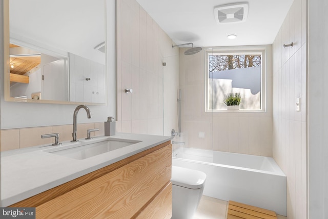 bathroom featuring toilet, vanity, visible vents, and bathing tub / shower combination