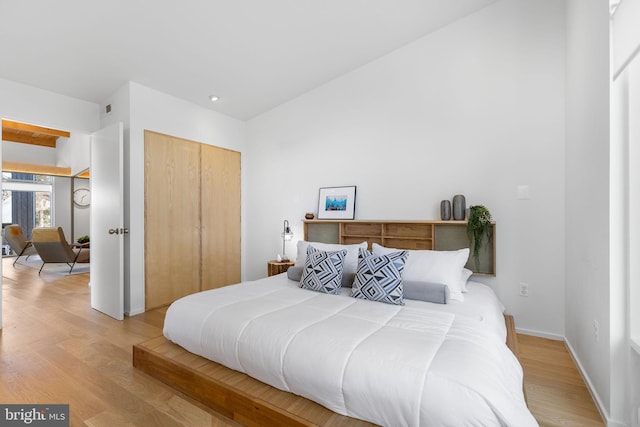 bedroom with light wood finished floors, a closet, visible vents, and baseboards