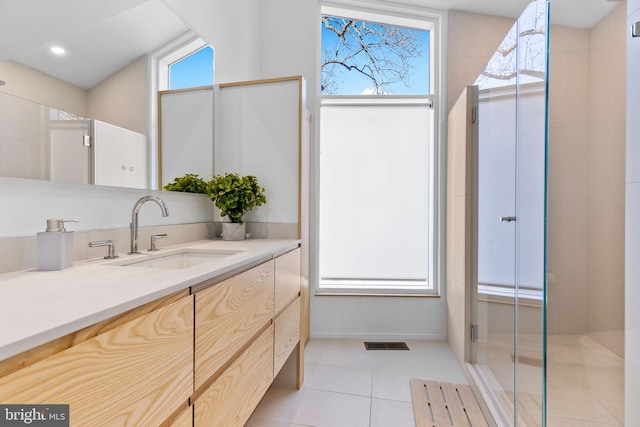 bathroom with a healthy amount of sunlight, a shower with door, tile patterned flooring, and visible vents