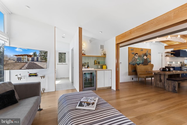 living room with a dry bar, beverage cooler, lofted ceiling with beams, and wood finished floors