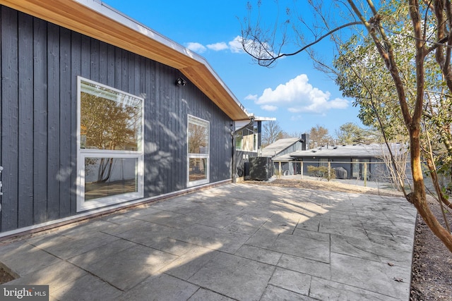 view of side of property with fence, central AC, and a patio