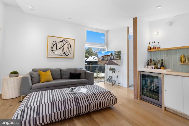 living room with wine cooler, light wood-type flooring, and a dry bar