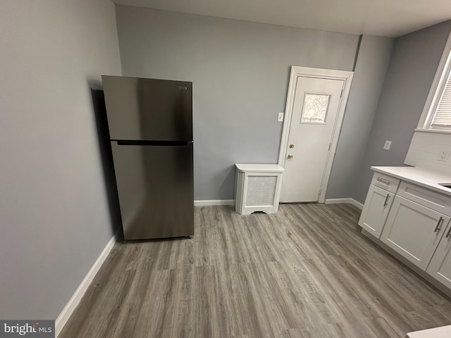 kitchen featuring stainless steel refrigerator, white cabinets, and light wood-type flooring