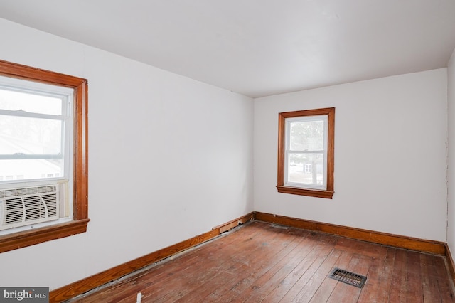 spare room featuring cooling unit, a healthy amount of sunlight, and wood-type flooring