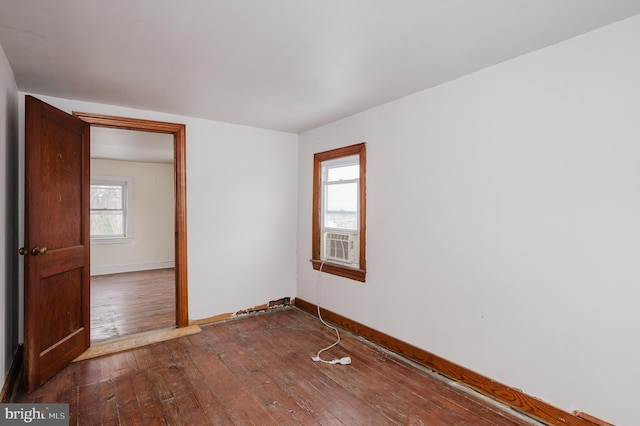 empty room featuring plenty of natural light, cooling unit, and dark hardwood / wood-style flooring