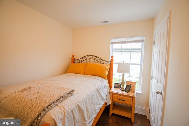 bedroom with baseboards, visible vents, and dark wood finished floors