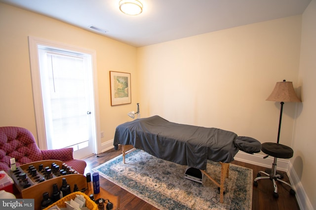 bedroom with wood finished floors, visible vents, and baseboards