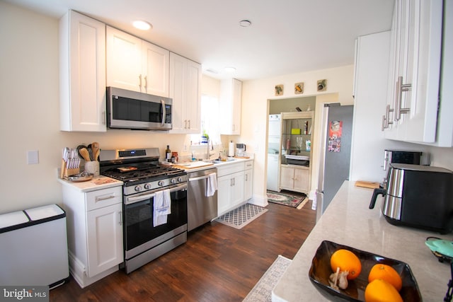 kitchen with dark hardwood / wood-style floors, white cabinetry, sink, and appliances with stainless steel finishes