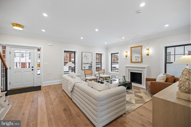 living room with a wealth of natural light, light hardwood / wood-style flooring, and crown molding