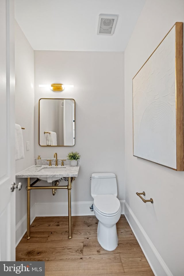 bathroom featuring hardwood / wood-style flooring, toilet, and sink